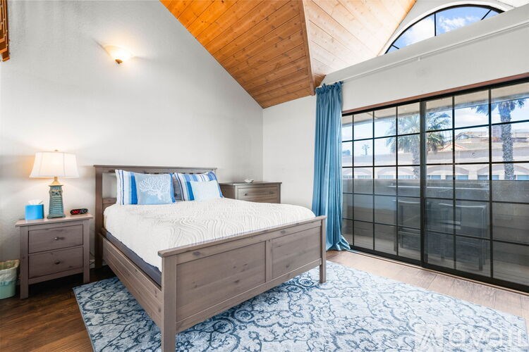 A bedroom with a large bed and a wooden ceiling.