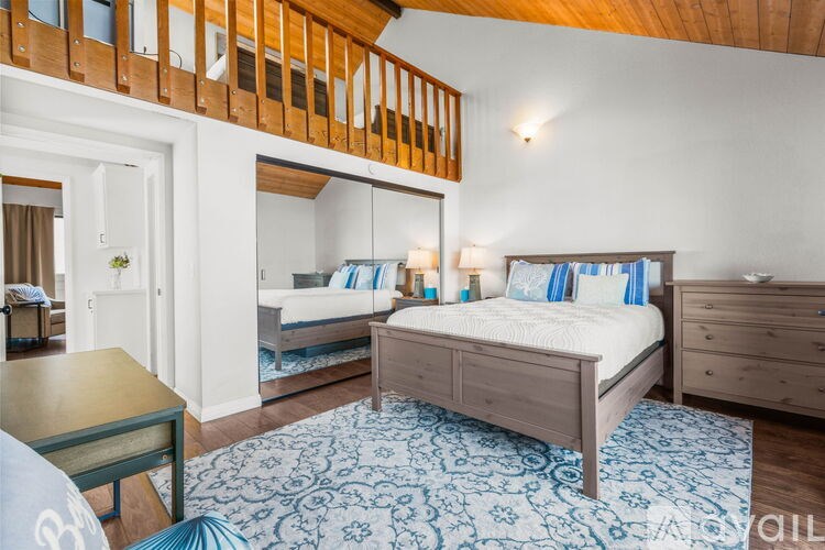 A bedroom with a large bed and a blue patterned rug.