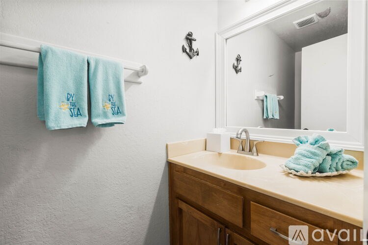 A bathroom with a sink, mirror, and towels hanging on a towel rack.