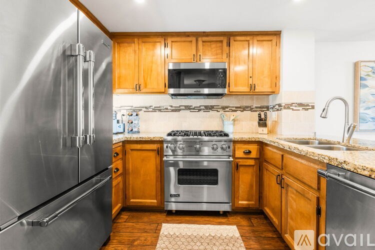 A kitchen with wooden cabinets and a stainless steel refrigerator.