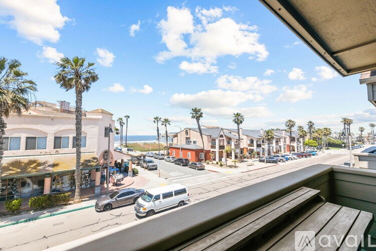A street view with cars and palm trees.