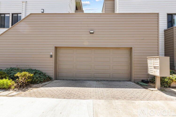 A garage door is closed and there is a sign on the right side of the garage.