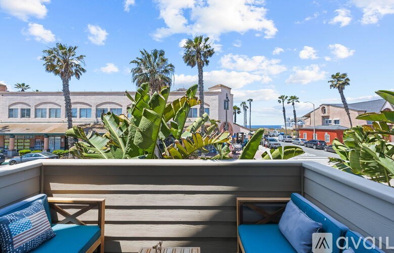 A balcony with blue cushions and a view of palm trees and buildings.