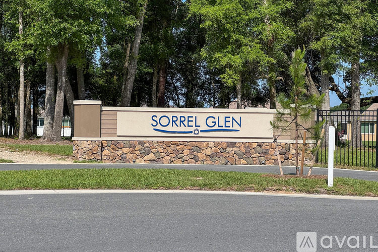 A sign that says "SORREL GLEN" in front of some trees.