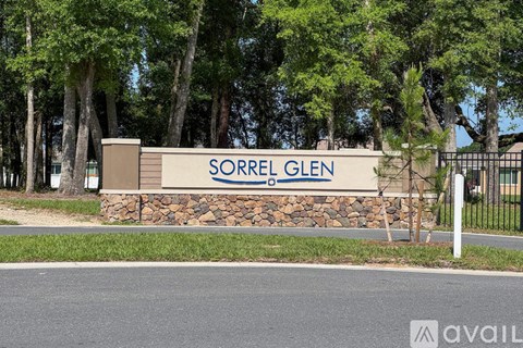 A sign that says "SORREL GLEN" in front of some trees.