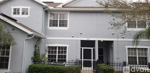 A grey house with a black fence in front.