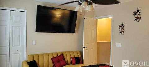 A living room with a yellow couch and a flat screen TV mounted on the wall.
