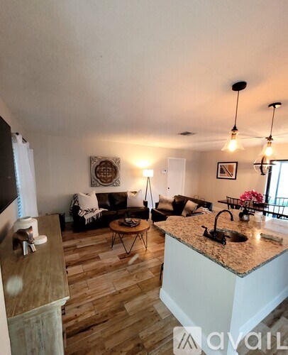 A kitchen with a white countertop and a sink, a living room with a couch and a coffee table, and a dining area with a table and chairs.