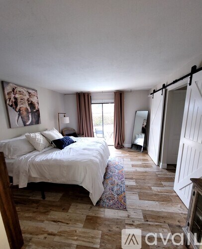 A bedroom with a bed, a mirror, and a painting of an elephant on the wall.