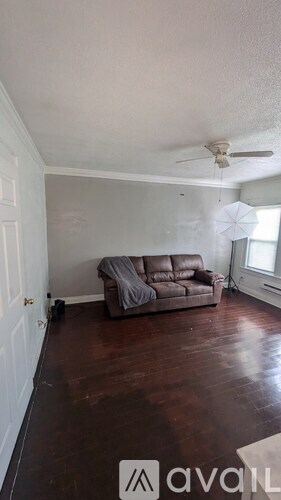 A living room with a couch and a fan.