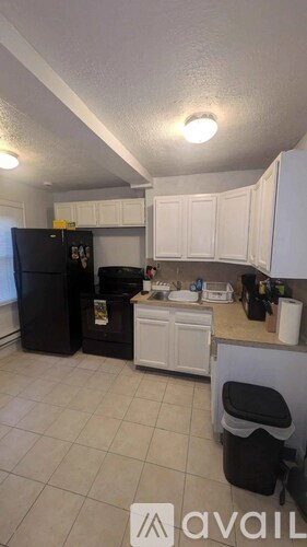 A kitchen with white cabinets and a black fridge.