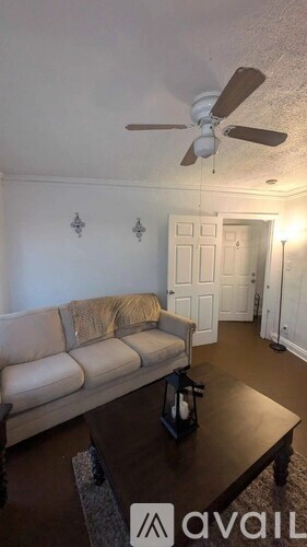 A living room with a couch, coffee table, and ceiling fan.