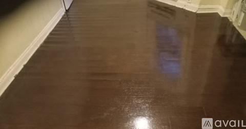 A dark wooden floor with a reflection of a light source.