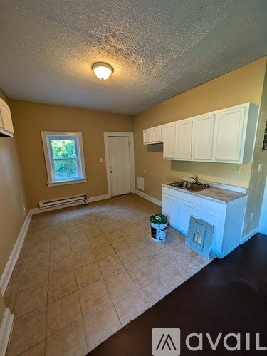 A room with a window, sink, and cabinets is available for rent.