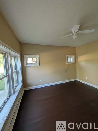 A room with a fan and two windows.