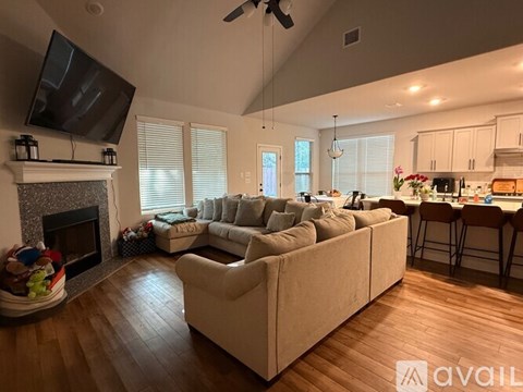 A living room with a fireplace and a television mounted above it.