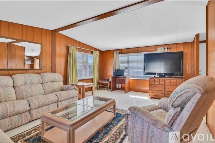 A living room with a sofa, a chair, a coffee table, and a television.