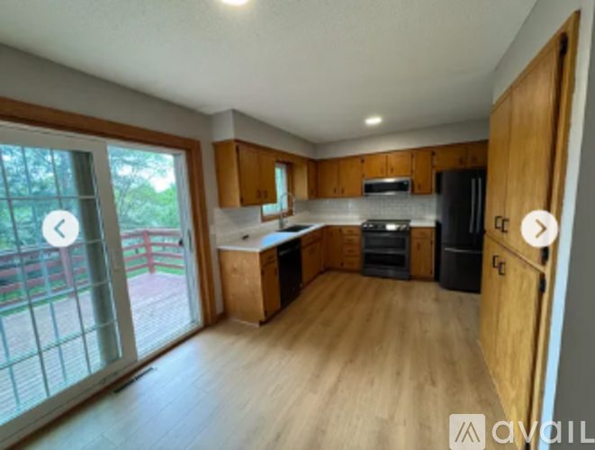 A kitchen with wooden cabinets and a black fridge.