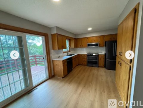 A kitchen with wooden cabinets and a black fridge.