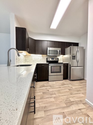 A kitchen with a white counter top and wooden flooring.