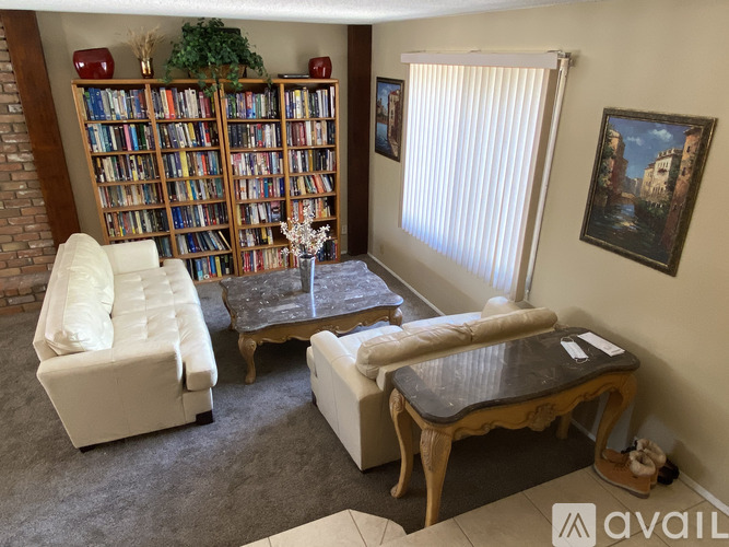 A living room with a bookshelf, a sofa, a coffee table, and a painting on the wall.