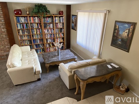 A living room with a bookshelf, a sofa, a coffee table, and a painting on the wall.