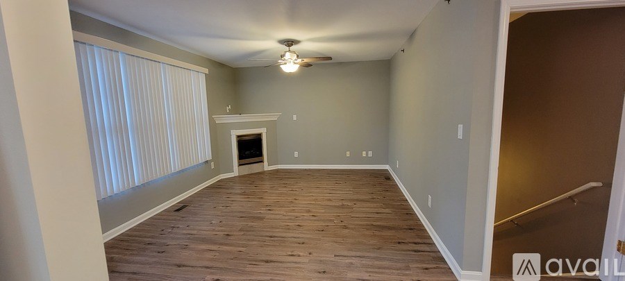 A spacious room with wood flooring and a fireplace.