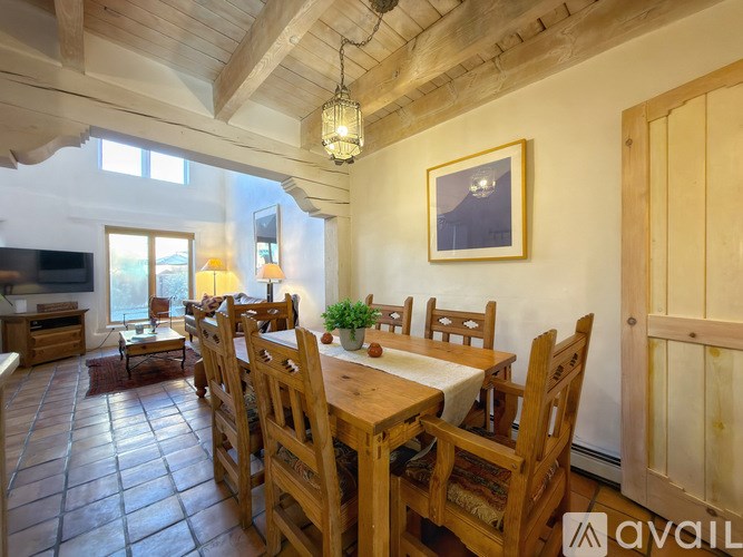 A wooden dining table with chairs and a hanging light fixture.