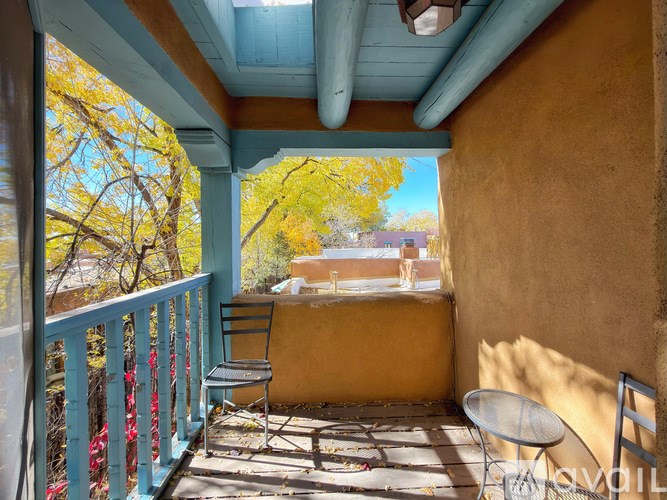 A balcony with a table and chairs overlooking a tree.