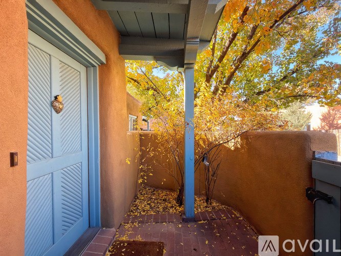 A blue door is on the left and a tree with yellow leaves is on the right.