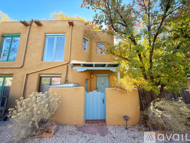 A yellow house with a blue door and a fence.