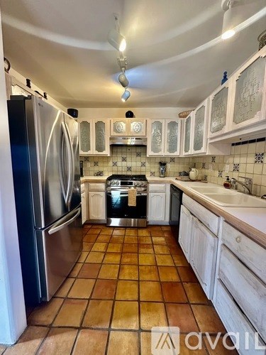 A kitchen with tile flooring and a stainless steel refrigerator.