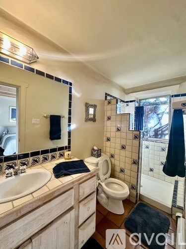 A bathroom with a sink, toilet, and mirror.