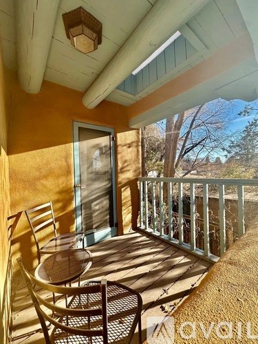 A balcony with a table and chairs is bathed in sunlight.