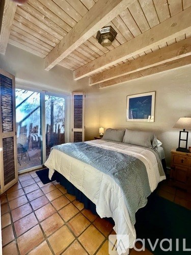 A bedroom with a bed, nightstand, and a painting on the wall.