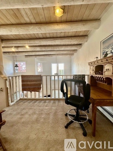 A room with a black chair and a wooden desk.