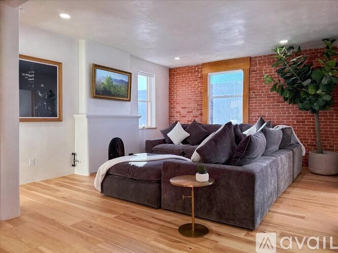 A living room with a grey couch, a small table, and a plant.