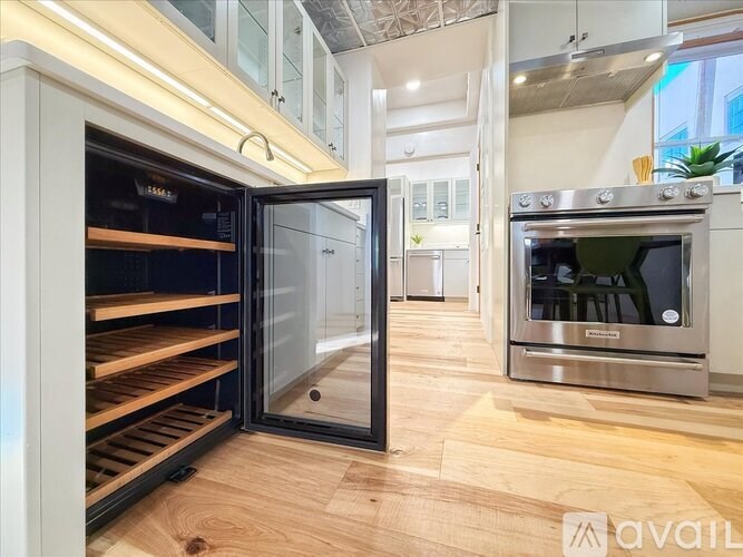 A modern kitchen with a stainless steel oven and wooden flooring.