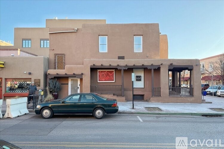 A green car is parked in front of a building with a red sign on the door.