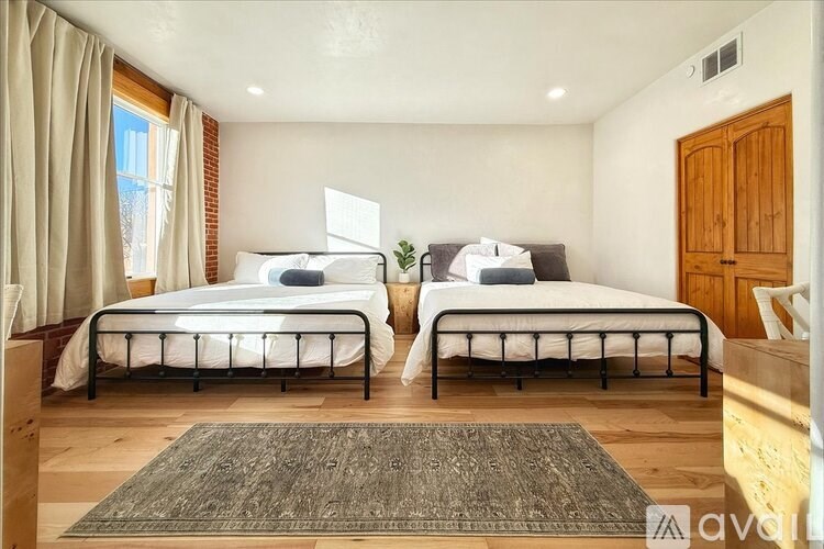 Two twin beds in a room with wooden floors and a rug.
