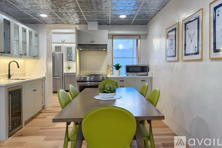 A kitchen with a table and chairs in the foreground and a fridge, oven, and other appliances in the background.