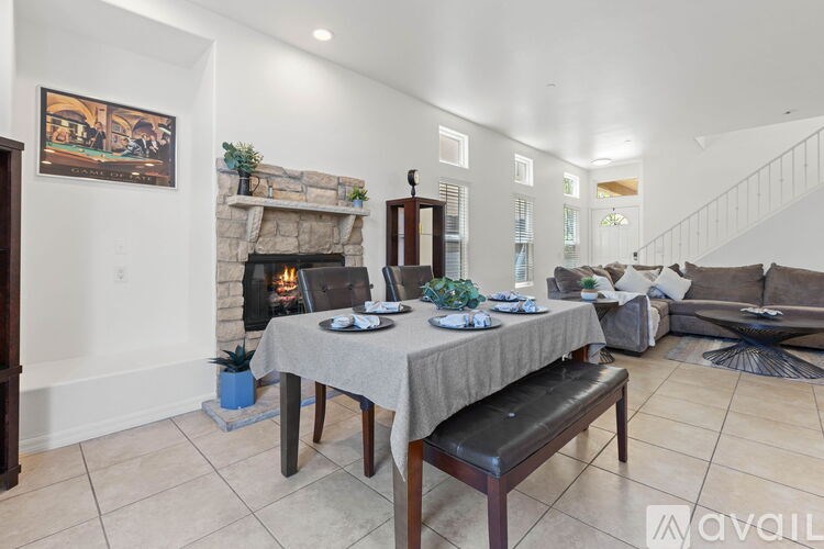 A dining room with a table set for two and a fireplace.