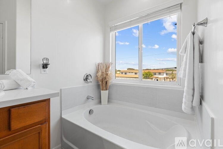A white bathroom with a large window overlooking a field.