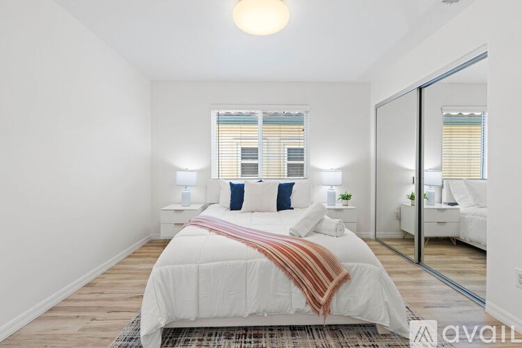 A bedroom with a large bed and a view of a window with blinds.