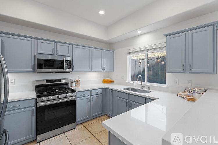 A kitchen with a white countertop and grey cabinets.