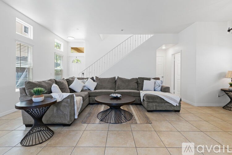 A living room with a grey couch, a black coffee table, and a white wall.
