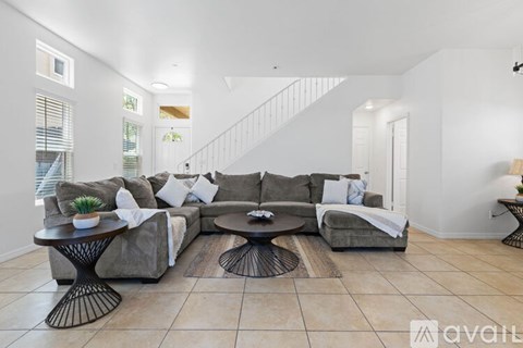 A living room with a grey couch, a black coffee table, and a white wall.