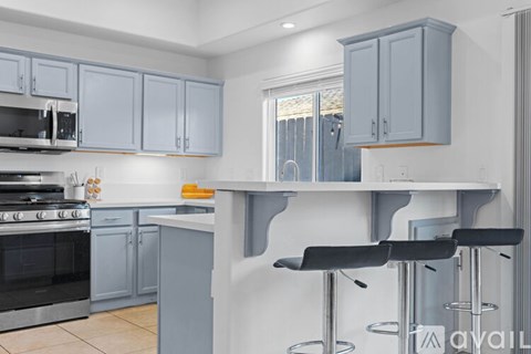 A kitchen with a black stove top oven and grey cabinets.