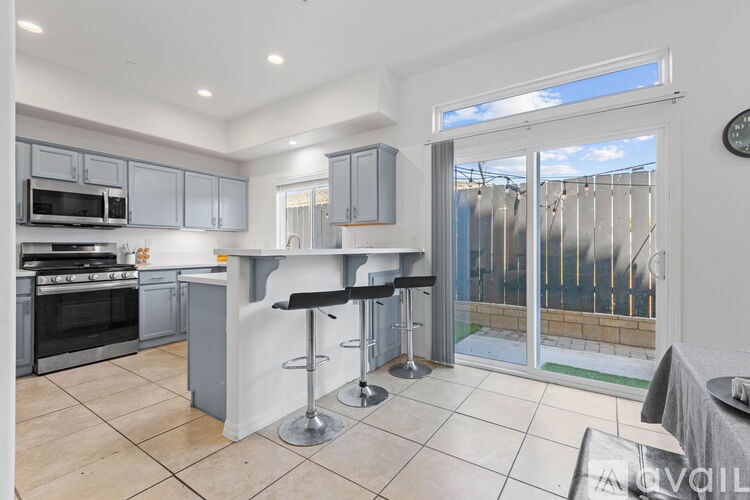 A modern kitchen with a bar stool and a clock on the wall.