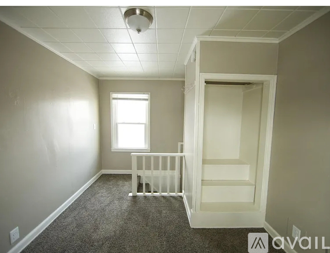 A baby crib sits in a corner of a room with a window.
